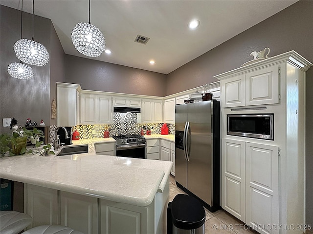 1530 Persimmon, Ardmore, OK 73401 - kitchen featuring appliances with stainless steel finishes, a peninsula, decorative backsplash, light countertops, and light tile patterned floors