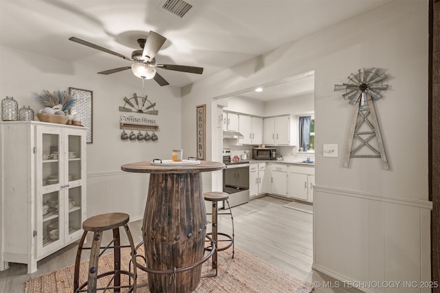15917 E 131st St Unit 93, Broken Arrow, OK 74011 - kitchen with stove, black microwave, light wood-style floors, white cabinets, and under cabinet range hood