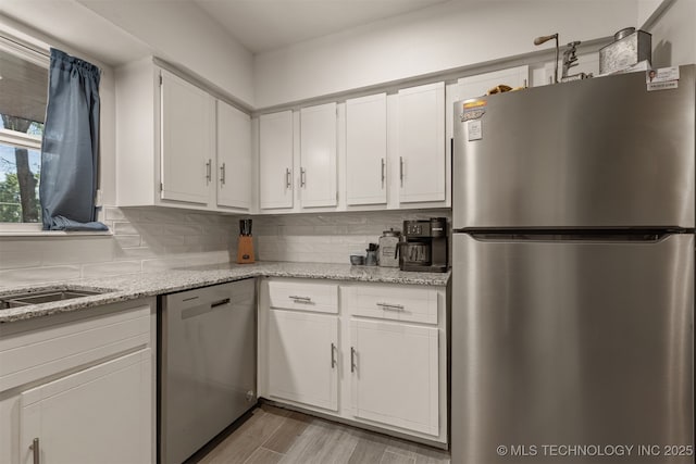 15917 E 131st St Unit 93, Broken Arrow, OK 74011 - kitchen with appliances with stainless steel finishes, white cabinets, decorative backsplash, light wood-type flooring, and light stone countertops