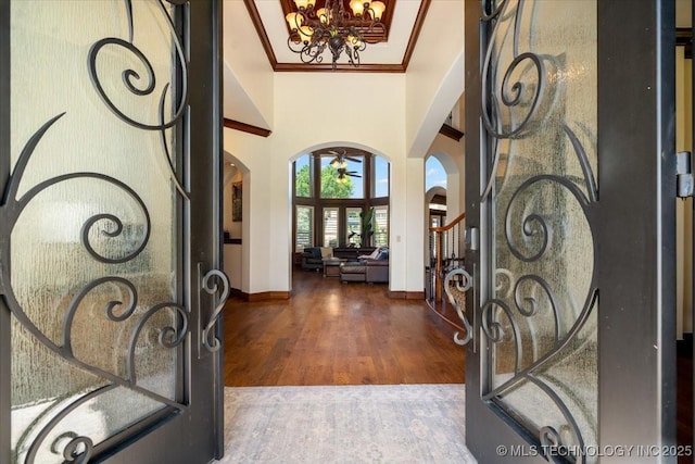 6797 Hummingbird Ct, Owasso, OK 74055 - foyer entrance with arched walkways, a chandelier, wood finished floors, crown molding, and a high ceiling