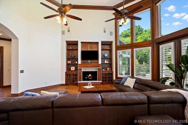 6797 Hummingbird Ct, Owasso, OK 74055 - living room with a ceiling fan, a towering ceiling, arched walkways, plenty of natural light, and wood finished floors