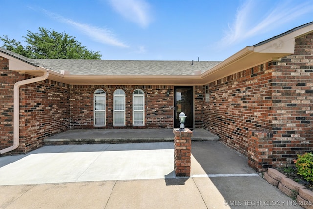 6627 Castle Ct, Bartlesville, OK 74006 - entrance to property featuring brick siding, roof with shingles, and a patio