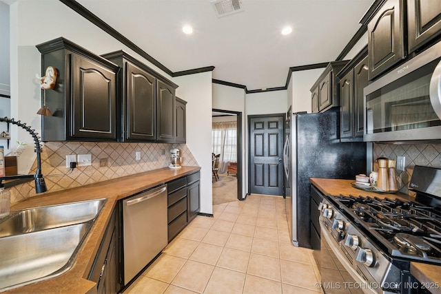 1018 W Evergreen St, Skiatook, OK 74070 - kitchen featuring stainless steel appliances, crown molding, butcher block counters, decorative backsplash, and light tile patterned flooring