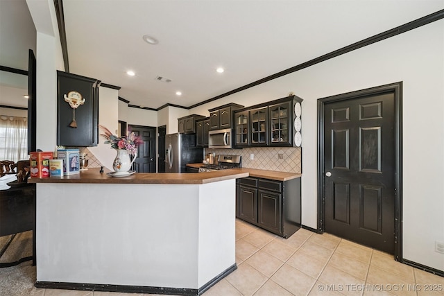1018 W Evergreen St, Skiatook, OK 74070 - kitchen with stainless steel appliances, backsplash, a peninsula, glass insert cabinets, and light tile patterned floors