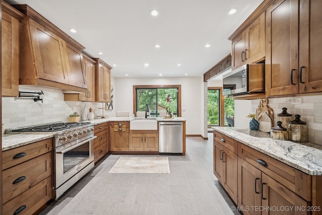 12526 S 12th St, Jenks, OK 74037 - kitchen with appliances with stainless steel finishes, a peninsula, recessed lighting, backsplash, and light stone countertops