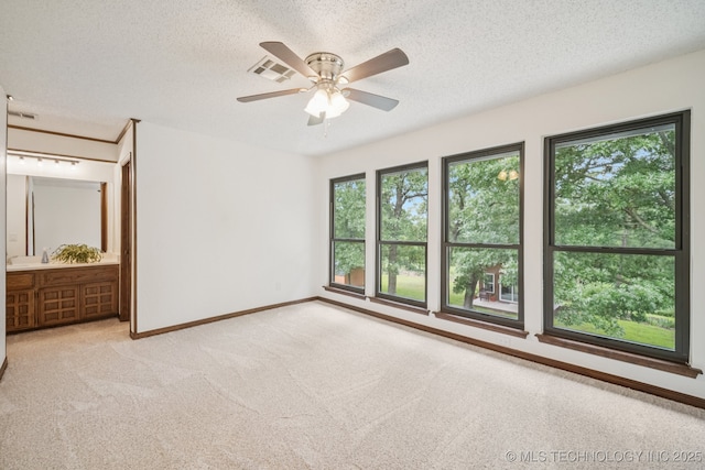 12526 S 12th St, Jenks, OK 74037 - unfurnished bedroom featuring multiple windows, a textured ceiling, light carpet, ensuite bath, and a ceiling fan