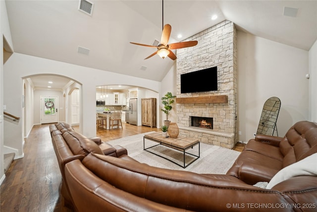 8404 E 98th Pl, Tulsa, OK 74133 - living room featuring a ceiling fan, arched walkways, a stone fireplace, light wood-style floors, and high vaulted ceiling