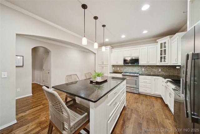8404 E 98th Pl, Tulsa, OK 74133 - kitchen featuring appliances with stainless steel finishes, crown molding, a kitchen breakfast bar, arched walkways, and backsplash