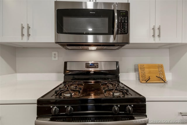 1510 S College Ave, Tulsa, OK 74104 - kitchen with stainless steel microwave, black gas range, light countertops, and white cabinets