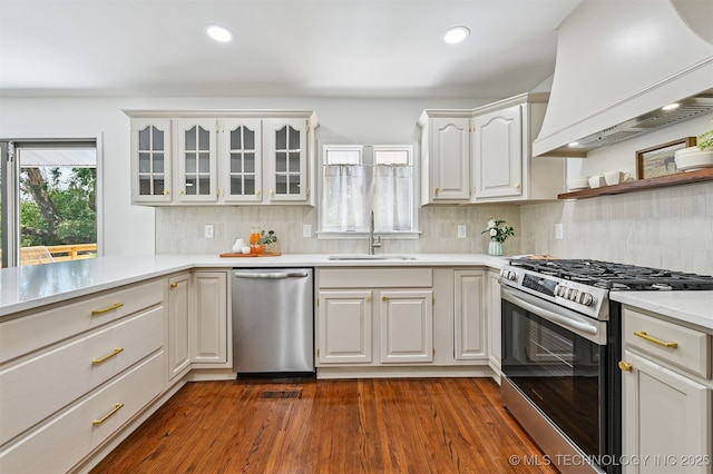 10 E 31st Pl, Sand Springs, OK 74063 - kitchen featuring appliances with stainless steel finishes, custom range hood, light countertops, glass insert cabinets, and tasteful backsplash