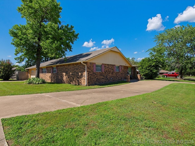 317 NE Autumn Ct, Bartlesville, OK 74006 - view of home's exterior with brick siding, a lawn, driveway, and an attached garage