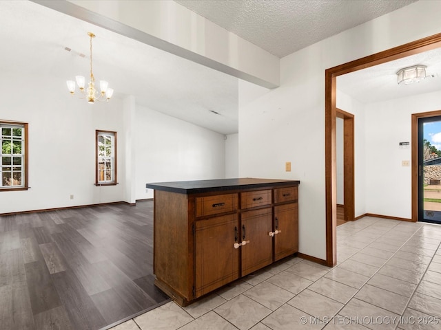 317 NE Autumn Ct, Bartlesville, OK 74006 - kitchen with dark countertops, a chandelier, pendant lighting, light wood-type flooring, and a peninsula