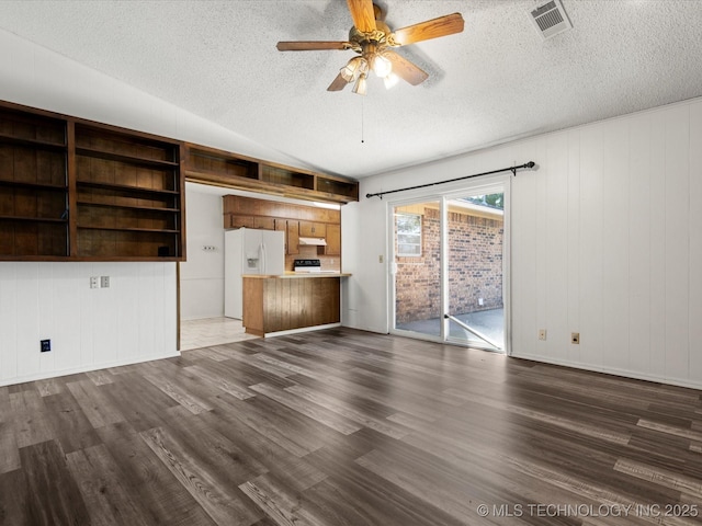 317 NE Autumn Ct, Bartlesville, OK 74006 - unfurnished living room featuring a textured ceiling, dark wood-type flooring, ceiling fan, and wooden walls