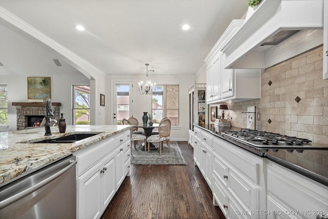 11248 S 75th Ave E, Bixby, OK 74008 - kitchen featuring appliances with stainless steel finishes, premium range hood, a chandelier, dark wood-type flooring, and a fireplace