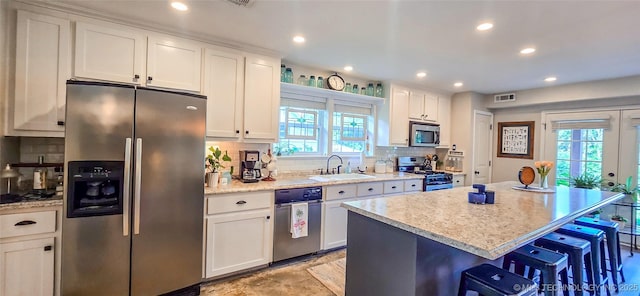 108256 Pike St, Checotah, OK 74426 - kitchen featuring appliances with stainless steel finishes, healthy amount of natural light, backsplash, a kitchen breakfast bar, and recessed lighting