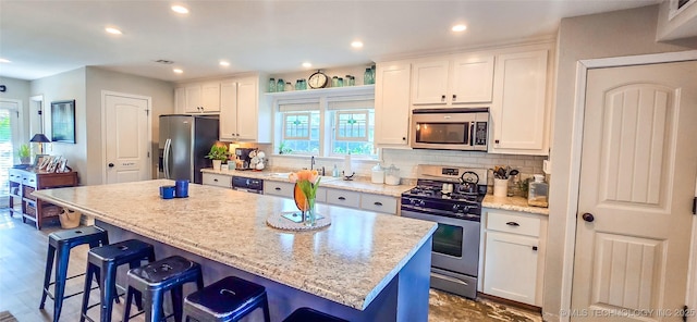 108256 Pike St, Checotah, OK 74426 - kitchen with stainless steel appliances, plenty of natural light, a kitchen island, white cabinets, and recessed lighting