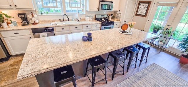 108256 Pike St, Checotah, OK 74426 - kitchen with stainless steel appliances, healthy amount of natural light, white cabinetry, and a breakfast bar