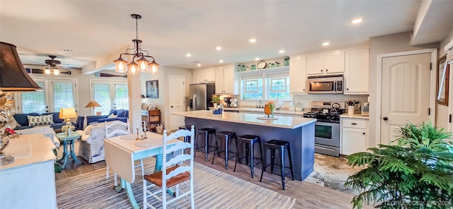 108256 Pike St, Checotah, OK 74426 - kitchen with appliances with stainless steel finishes, a breakfast bar, white cabinetry, a center island, and a ceiling fan