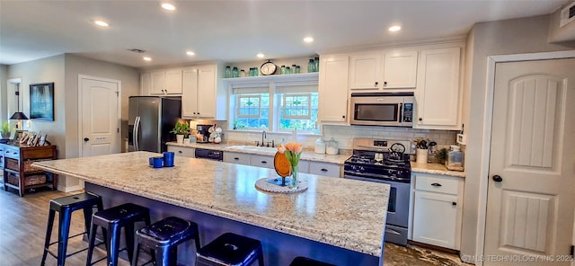108256 Pike St, Checotah, OK 74426 - kitchen with appliances with stainless steel finishes, white cabinets, a kitchen breakfast bar, decorative backsplash, and a center island