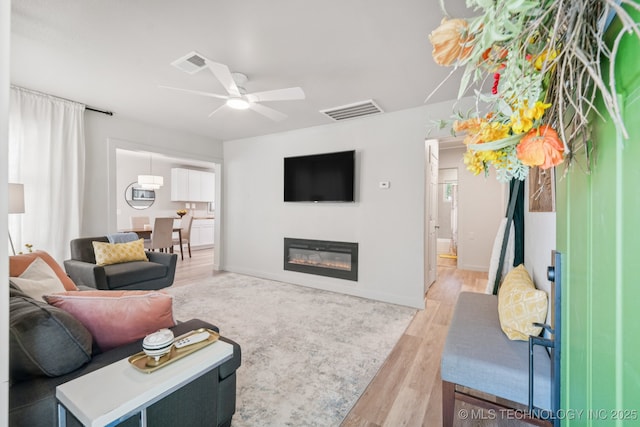 2837 E Admiral Ct, Tulsa, OK 74110 - living area with ceiling fan, light wood-type flooring, and a glass covered fireplace
