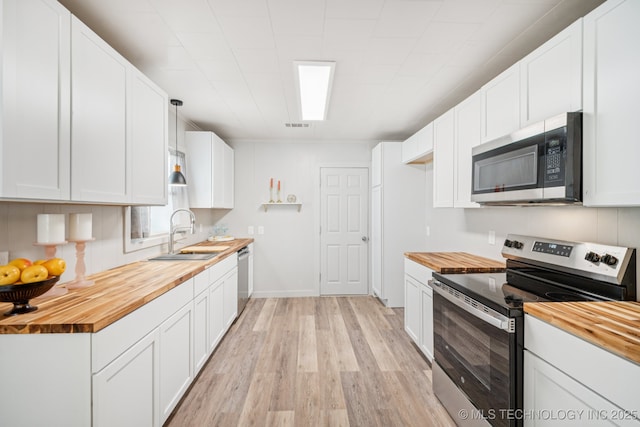 2837 E Admiral Ct, Tulsa, OK 74110 - kitchen with butcher block countertops, stainless steel appliances, light wood-style floors, and white cabinetry