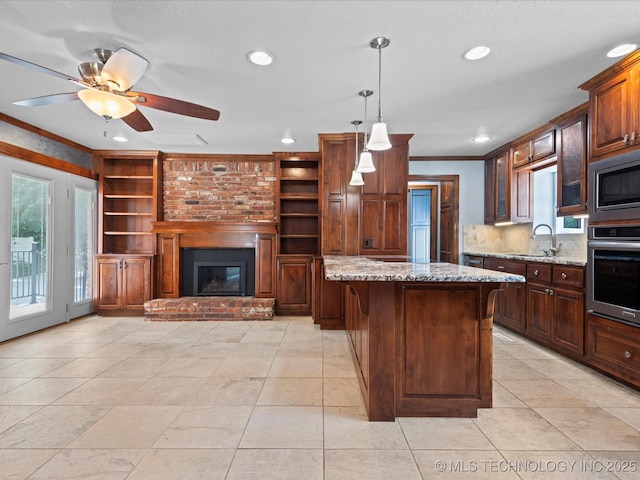 927 Macklyn Ln, Bartlesville, OK 74006 - kitchen featuring stainless steel appliances, ornamental molding, light stone counters, recessed lighting, and a fireplace