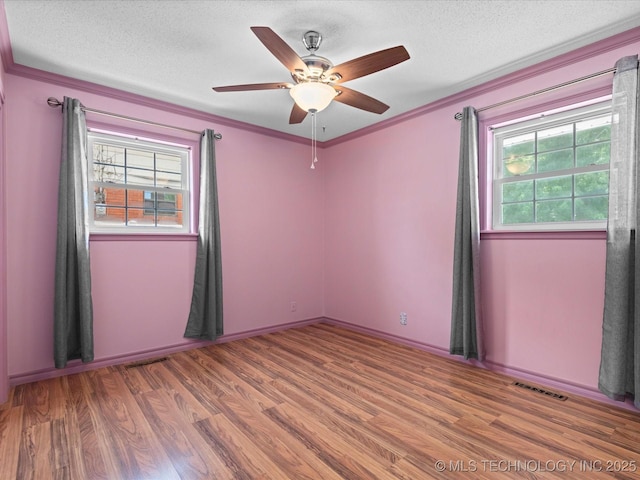 927 Macklyn Ln, Bartlesville, OK 74006 - empty room featuring healthy amount of natural light, wood finished floors, a textured ceiling, a ceiling fan, and ornamental molding