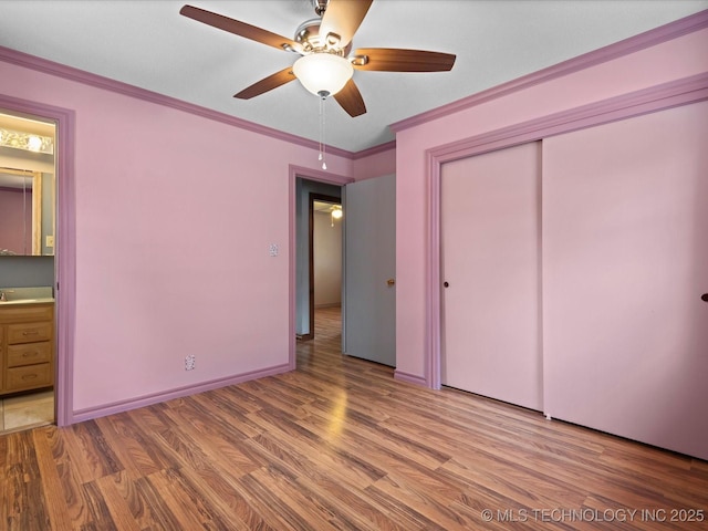 927 Macklyn Ln, Bartlesville, OK 74006 - unfurnished bedroom with wood finished floors, a closet, ensuite bath, crown molding, and a ceiling fan
