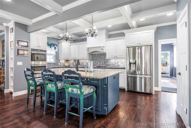 1528 Smysor Dr, Bartlesville, OK 74006 - kitchen with appliances with stainless steel finishes, a chandelier, coffered ceiling, white cabinetry, and dark wood-style floors