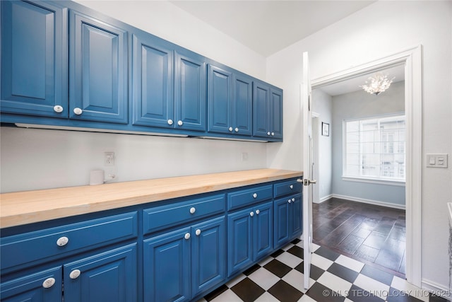 1528 Smysor Dr, Bartlesville, OK 74006 - kitchen featuring wooden counters, blue cabinets, dark flooring, and a chandelier