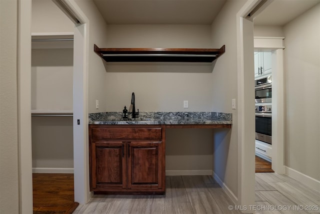 7141 E 138th Pl, Collinsville, OK 74021 - indoor wet bar featuring light wood-style flooring and stainless steel double oven