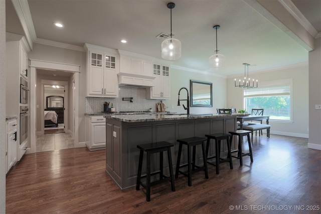 7141 E 138th Pl, Collinsville, OK 74021 - kitchen featuring a kitchen bar, ornamental molding, white cabinetry, dark wood finished floors, and glass insert cabinets