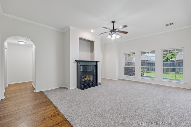 2629 S 13th St, Broken Arrow, OK 74012 - unfurnished living room featuring crown molding, ceiling fan, arched walkways, a fireplace with flush hearth, and wood finished floors