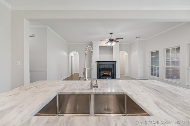 2629 S 13th St, Broken Arrow, OK 74012 - kitchen with arched walkways, light stone counters, a fireplace, ceiling fan, and crown molding