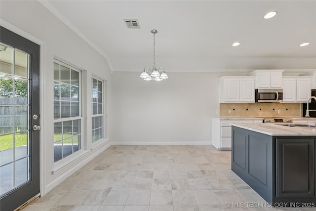 2629 S 13th St, Broken Arrow, OK 74012 - kitchen with stainless steel microwave, white cabinets, a chandelier, decorative light fixtures, and decorative backsplash