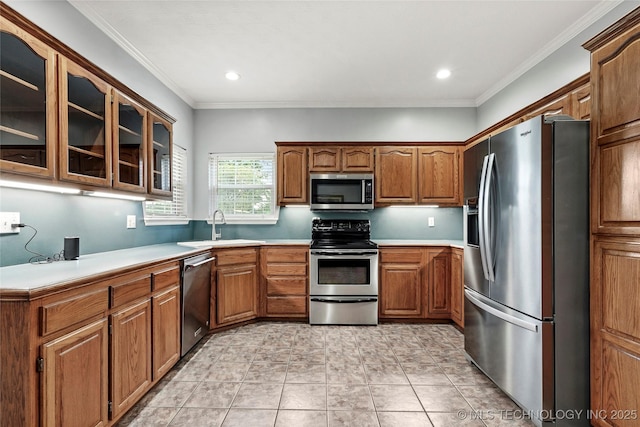 10672 E Canyon Oaks Ct, Claremore, OK 74017 - kitchen featuring stainless steel appliances, brown cabinets, glass insert cabinets, light countertops, and ornamental molding