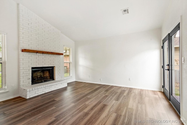 1847 W 57th Pl, Tulsa, OK 74107 - unfurnished living room with wood finished floors, a brick fireplace, and vaulted ceiling
