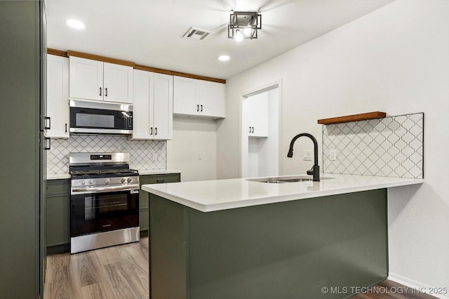 1847 W 57th Pl, Tulsa, OK 74107 - kitchen with appliances with stainless steel finishes, a peninsula, light wood-type flooring, white cabinets, and recessed lighting