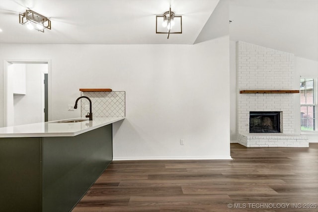 1847 W 57th Pl, Tulsa, OK 74107 - kitchen featuring vaulted ceiling, wood finished floors, a brick fireplace, light countertops, and open floor plan