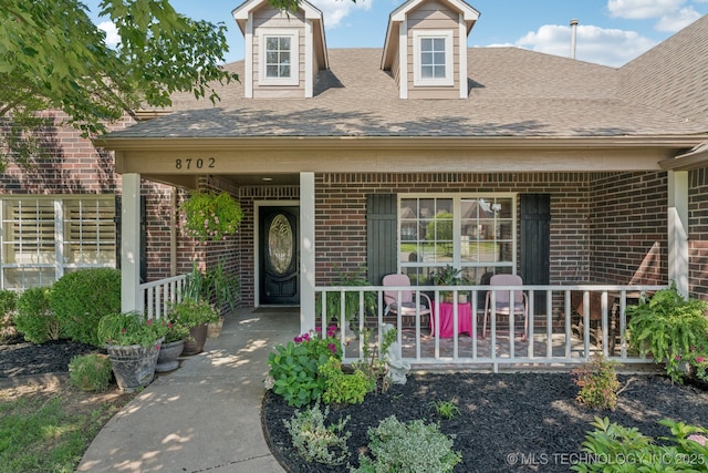 8702 N 140th Ter, Owasso, OK 74055 - doorway to property featuring brick siding, a porch, and a shingled roof
