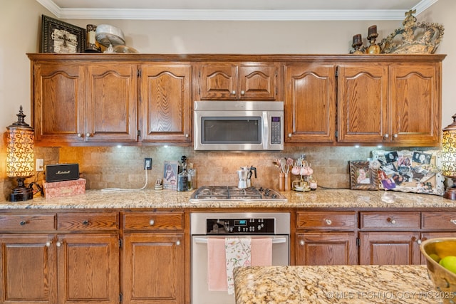 8702 N 140th Ter, Owasso, OK 74055 - kitchen with stainless steel appliances, ornamental molding, brown cabinetry, backsplash, and light stone counters