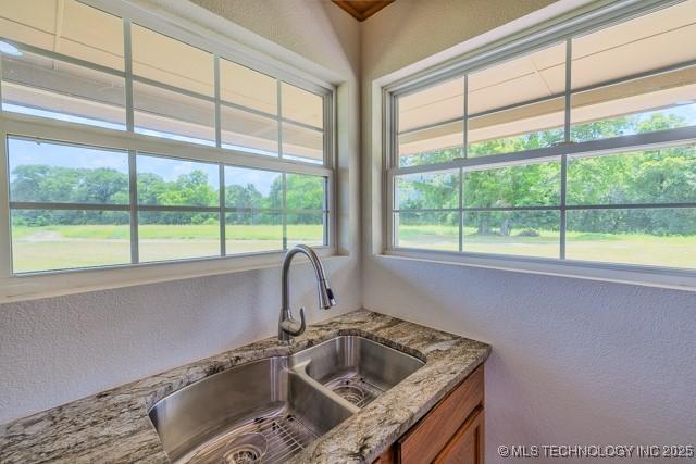 16547 County Road 1600, Ada, OK 74820 - kitchen with a textured wall, brown cabinetry, and light stone counters