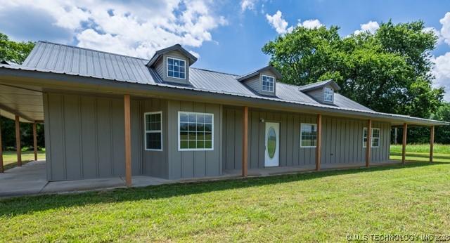 16547 County Road 1600, Ada, OK 74820 - back of property with board and batten siding, a lawn, and a metal roof