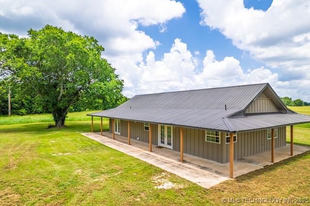 16547 County Road 1600, Ada, OK 74820 - back of house featuring a lawn, board and batten siding, french doors, and a metal roof