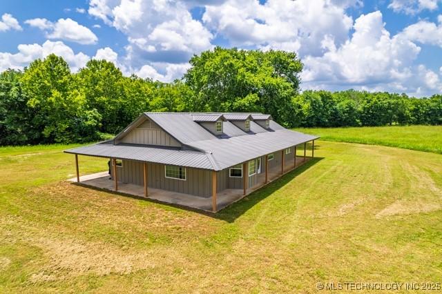 16547 County Road 1600, Ada, OK 74820 - rear view of house with board and batten siding, a yard, and a metal roof