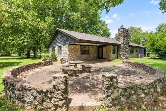 12725 S 168th E Ave, Broken Arrow, OK 74011 - back of property featuring stone siding, a chimney, a carport, and a yard