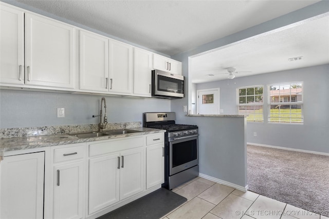 6711 E 10th St, Tulsa, OK 74112 - kitchen featuring appliances with stainless steel finishes, white cabinetry, light colored carpet, light stone countertops, and ceiling fan