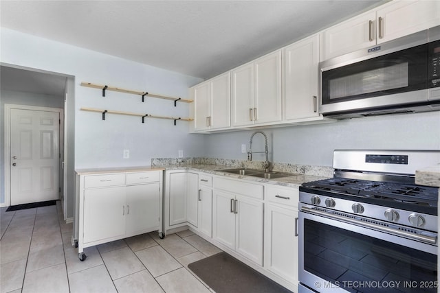 6711 E 10th St, Tulsa, OK 74112 - kitchen with appliances with stainless steel finishes, open shelves, white cabinetry, and light tile patterned flooring