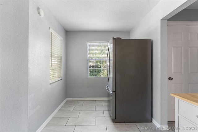 6711 E 10th St, Tulsa, OK 74112 - kitchen with freestanding refrigerator, white cabinets, a textured wall, light tile patterned floors, and a textured ceiling