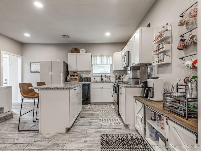 310 W Lee Ave, Sapulpa, OK 74066 - kitchen featuring freestanding refrigerator, dishwasher, a kitchen breakfast bar, a kitchen island, and decorative backsplash
